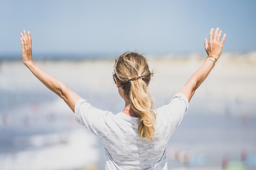 Vrouw op het strand met armen wijd omhoog